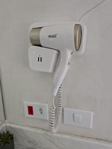 ein weißer Haartrockner, der an einer Wand hängt in der Unterkunft ensueños in Búzios