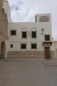 een wit gebouw met een bruine deur op een straat bij Riad Dalal in Fès