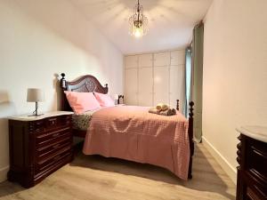 una camera da letto con un letto con lenzuola rosa e un comò di Santa Luzia pokoje a Funchal
