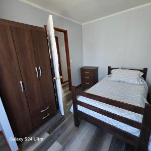 ein Schlafzimmer mit einem Bett und einem Holzschrank in der Unterkunft Casa en Frutillar in Frutillar