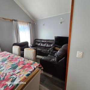 ein Wohnzimmer mit einem Ledersofa und einem Bett in der Unterkunft Casa en Frutillar in Frutillar