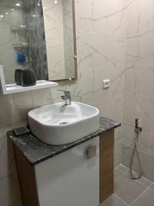 een badkamer met een witte wastafel en een spiegel bij Apartment in a residence with pool in Mohammedia