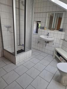 a white tiled bathroom with a shower and a sink at Ferienwohnung Thomée in Looft