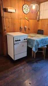a kitchen with a stove and a table and a clock at Ferienhütte See 4 in Seeberg