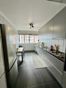 een grote keuken met witte kasten en een tafel bij City center Loreto in Ponta Delgada