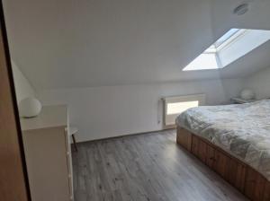 een slaapkamer met een bed en een dakraam bij Ferienwohnung Thomée in Looft