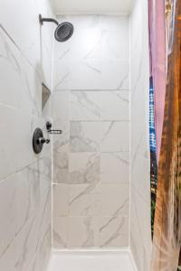 a bathroom with a shower with white marble tiles at Impeccable 1BR unit in Brooklyn in Brooklyn +5 photos