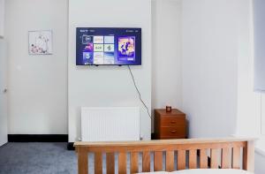 a room with a bench and a tv on the wall at Cosy Luxe Manchester Home With Fresh Bakes in Manchester