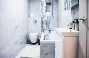 a white bathroom with a toilet and a sink at Cosy Luxe Manchester Home With Fresh Bakes in Manchester +27 photos