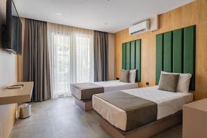 a hotel room with two beds and a television at Perast Garden Hotel in Cıralı