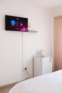 a room with a tv on the wall next to a refrigerator at Tasha Coastal Accommodation in Walvis Bay +45 photos