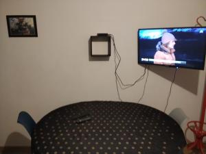 ein Raum mit einem Tisch und einem Fernseher an der Wand in der Unterkunft Le repos beaurepairien in Beaurepaire