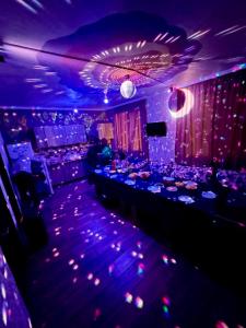 a room with a bar with purple lights and tables at Holiday house Tbilisi in Tbilisi City
