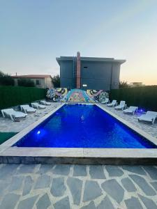 a blue swimming pool with chairs and a building at Holiday house Tbilisi in Tbilisi City