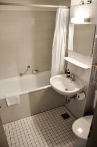 een badkamer met een wastafel, een bad en een toilet bij Hotel Rössle in Schongau