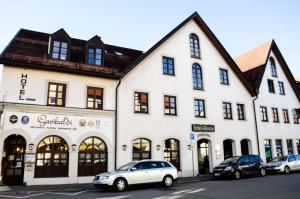 een wit gebouw met auto's ervoor geparkeerd bij Hotel Rössle in Schongau