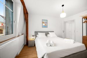 a white bedroom with a white bed with two white shoes on it at La Suite du Bourg in La Tour-de-Peilz
