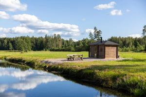 einen Picknicktisch und eine Bank neben einem Fluss in der Unterkunft Cope un Pirts in Yumprava