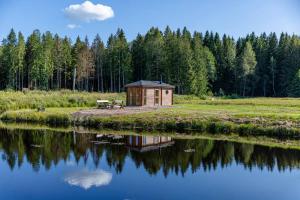 eine kleine Holzhütte neben einem Wasserkörper in der Unterkunft Cope un Pirts in Yumprava