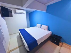 een blauwe kamer met een bed en een televisie bij Hotel Casa Manzanares in Santa Marta