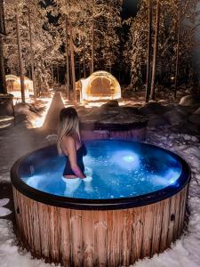 a girl sitting in a hot tub in the snow at Adults Only Invisible Forest Lodge & SPA in Rovaniemi