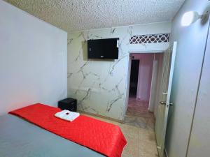 een slaapkamer met een rood bed en een tv aan de muur bij Hotel Casa Manzanares in Santa Marta