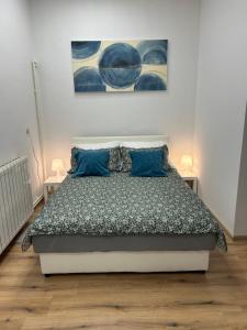 - une chambre avec un lit doté d'oreillers bleus et d'un tableau dans l'établissement Studio apartman MARIA 2, 