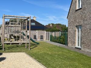 a playground in a yard next to a house at Huis Marlin in De Haan