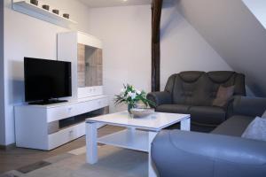 uma sala de estar com uma televisão, um sofá e uma mesa em Apartments anno 1560 em Quedlinburg