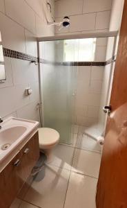 een badkamer met een douche, een toilet en een wastafel bij Suítes litoral in Caraguatatuba