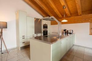 a kitchen with white cabinets and a wooden ceiling at Turuwang Penthouse by HomeFlow in Zermatt +8 photos