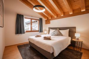 a bedroom with a large bed with a window at Turuwang Penthouse by HomeFlow in Zermatt