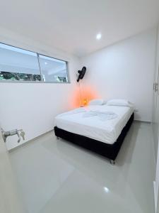 een witte slaapkamer met een bed en een raam bij Apartamento con piscina y Aire Acondicionado en Anapoima centro in Anapoima +4 foto's