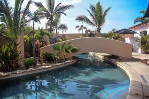 a swimming pool with a bridge and palm trees at The Cerritos Beach Inn in El Pescadero