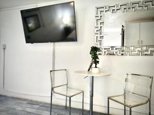 two chairs and a table with a tv on a wall at SEGOVIA STUDIO UNITS in Carolina