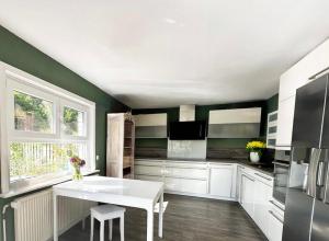 eine Küche mit grünen Wänden und einem weißen Tisch in der Unterkunft Waldgeflüster in Buchholz in der Nordheide