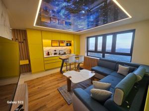 a living room with a blue couch and a kitchen at Apartman Blue Sky in Jahorina