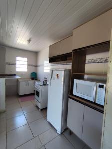 een keuken met een witte koelkast en een magnetron bij Kitnet em Arroio do Sal in Arroio do Sal