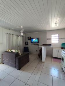 een woonkamer met een bank, een tafel en een tv bij Kitnet em Arroio do Sal in Arroio do Sal