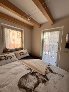 a bedroom with a large bed and two windows at Alpen Lodge Predazzo in Predazzo