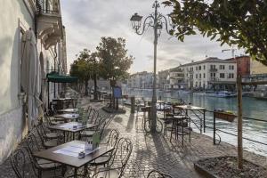 una caffetteria all'aperto con tavoli e sedie accanto a un fiume di Residenza Amé Peschiera del Garda a Peschiera del Garda