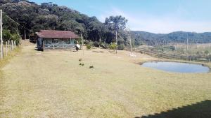 a small building in a field with a pond at Chácara Betel in Rancho Queimado
