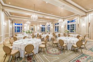 a banquet room with white tables and chairs and chandeliers at The George Washington - A Wyndham Grand Hotel in Winchester