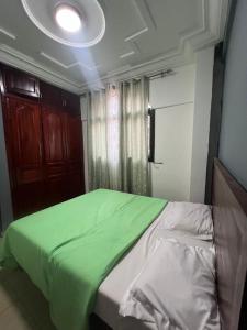 a bedroom with a bed with a green blanket at Fadilimmo 009 in Yaoundé