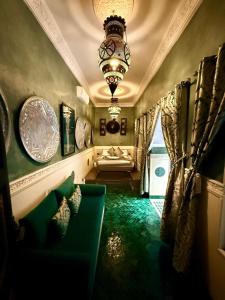 a living room with a green couch and a chandelier at Riad Ta'achchaqa in Marrakech +97 photos
