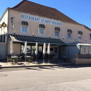 een restaurant met stoelen en parasols voor een gebouw bij Le Saint Germain in Saint-Germain-du-Bois