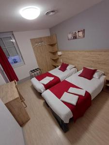 twee bedden in een kamer met rode en witte lakens bij Le Saint Germain in Saint-Germain-du-Bois