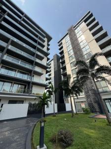 twee hoge gebouwen met palmbomen in een park bij Nova by Devtraco plus in Accra