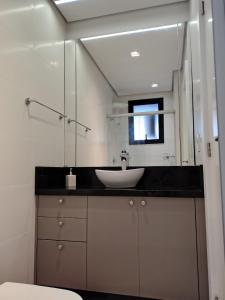 een badkamer met een wastafel en een spiegel bij Sinta se em casa, mas, com sol e mar in Torres