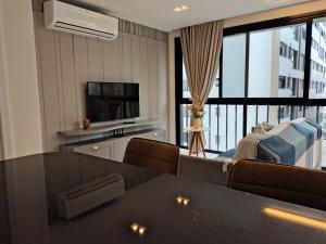 een woonkamer met een tafel, een bank en een televisie bij Sinta se em casa, mas, com sol e mar in Torres